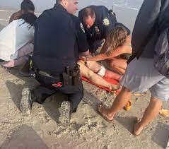 Police Officers apply tourniquets to the victim of a recent shark attack.