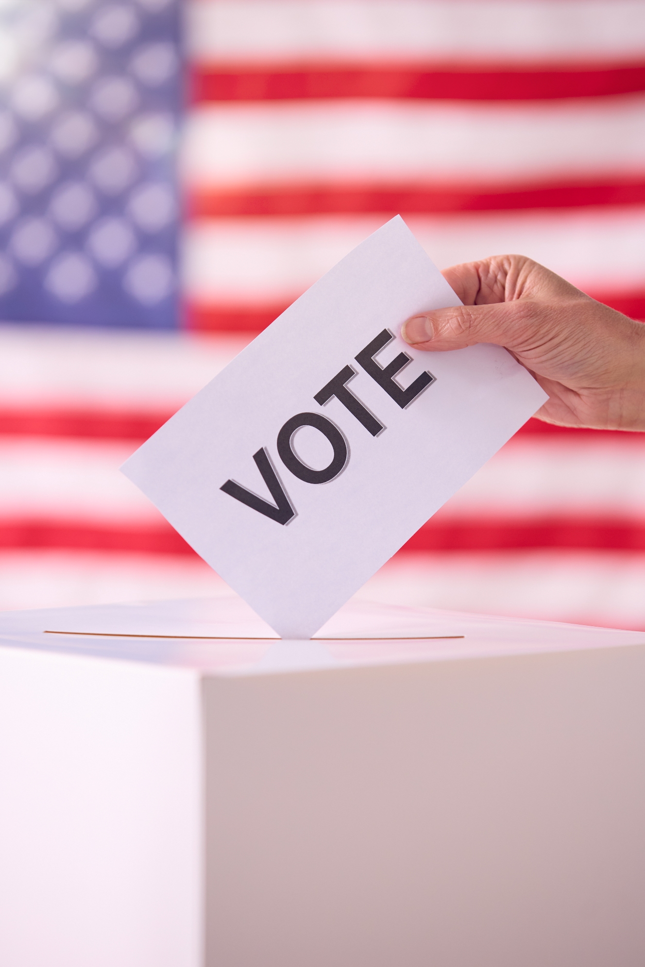 Hand Placing Vote In Ballot Box With American Flag Background Hand Placing Vote In Ballot Box With American Flag Background